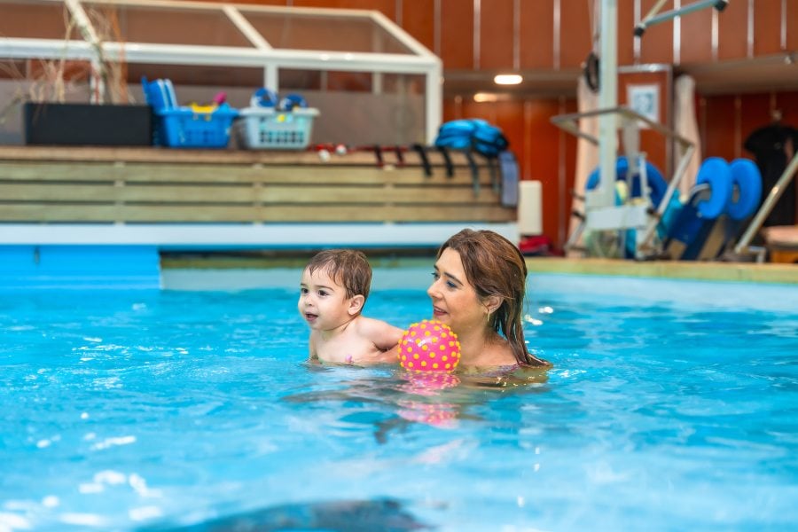 Baby auf dem Arm von der Mutter im Wasser