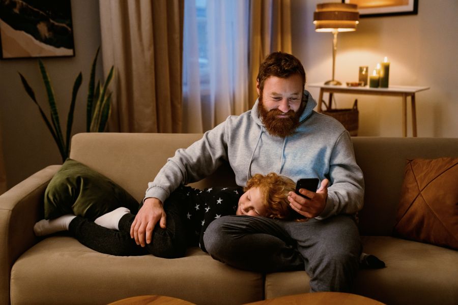Vater und Sohn abends auf der Couch am Handy