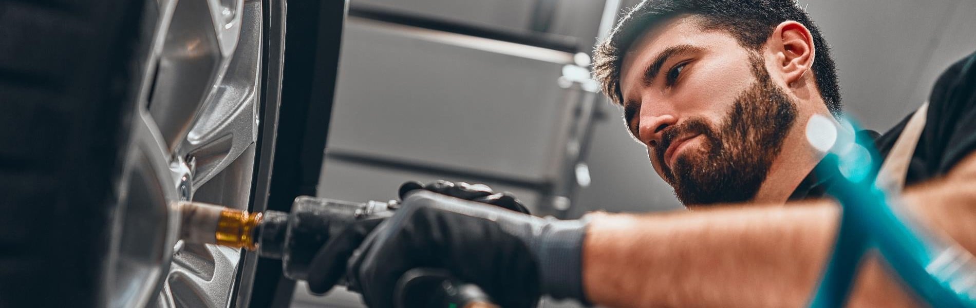 Kfz-Mechaniker schraubt einen Reifen