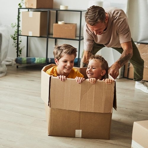 Vater mit zwei Buben, die in der Kiste geschoben werden