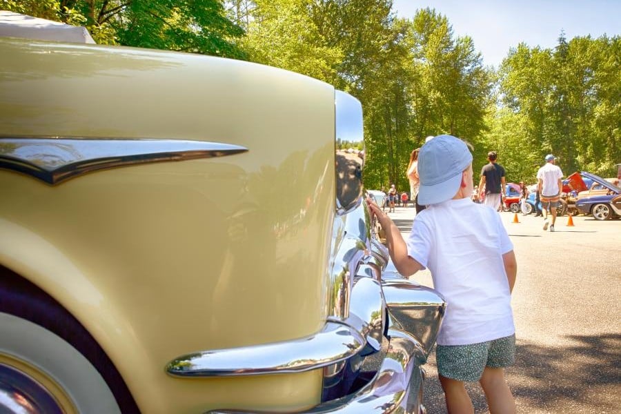 Kind steht neben einem OIdtimer