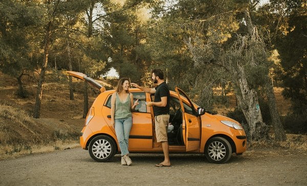 Mann und Frau stehen neben einem Auto und reden miteinander