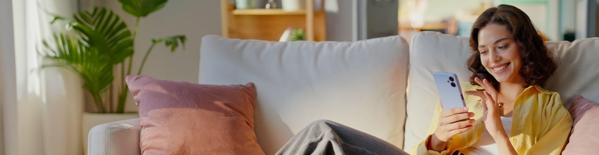 Frau sitzt mit Handy auf dem Couch