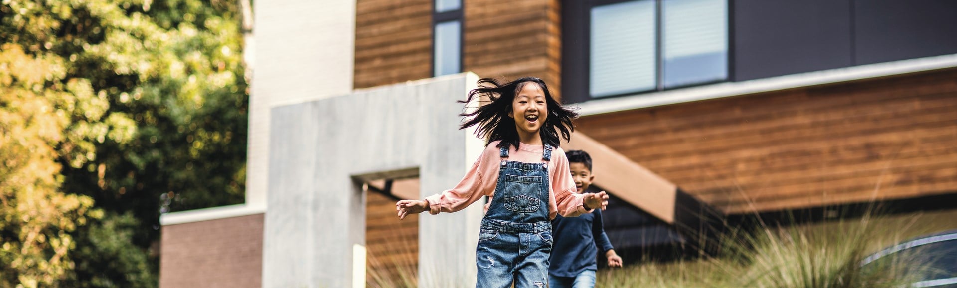 Kind lacht vor einem Haus
