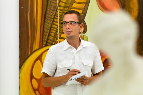 Mann steht in einem Atelier und schreibt was auf