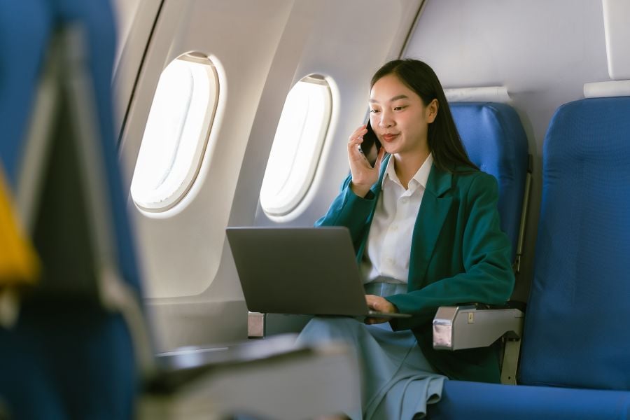 Frau sitzt im Flugzeug und tippt aud Laptoptastatur