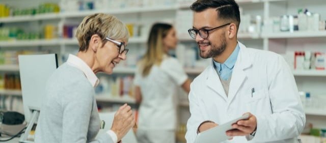 Frau in der Apotheke spricht mit Apotheker