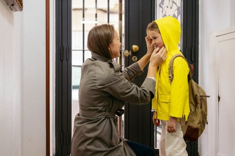 Mutter zieht dem Kind eine Regenjacke an