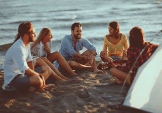 Junge Erwachsene sitzen gemeinsam am Strand