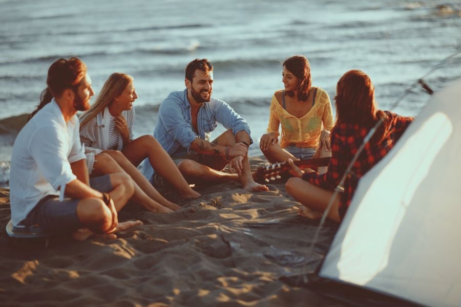 Junge Erwachsene sitzen gemeinsam am Strand