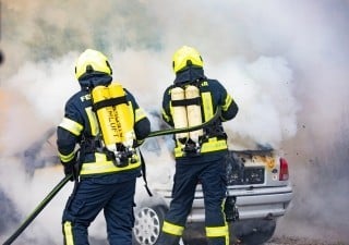 Feuerwehrmänner löschen brennendes Auto