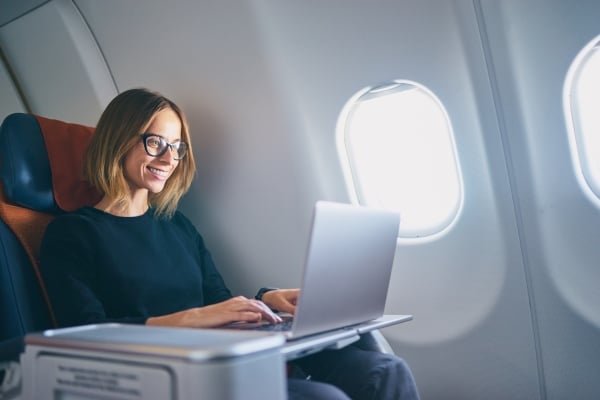 Frau arbeite am Laptop im Flugzeug